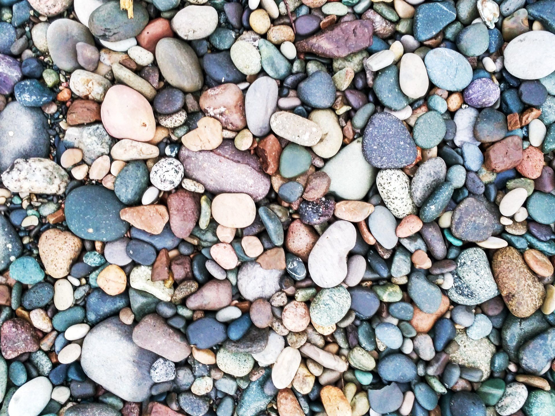Close-up of smooth multicolored pebbles in shades of blue, pink, gray, and tan.