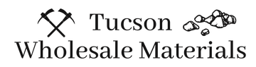 Tucson Wholesale Materials logo with crossed pickaxes and rocks in black and gray