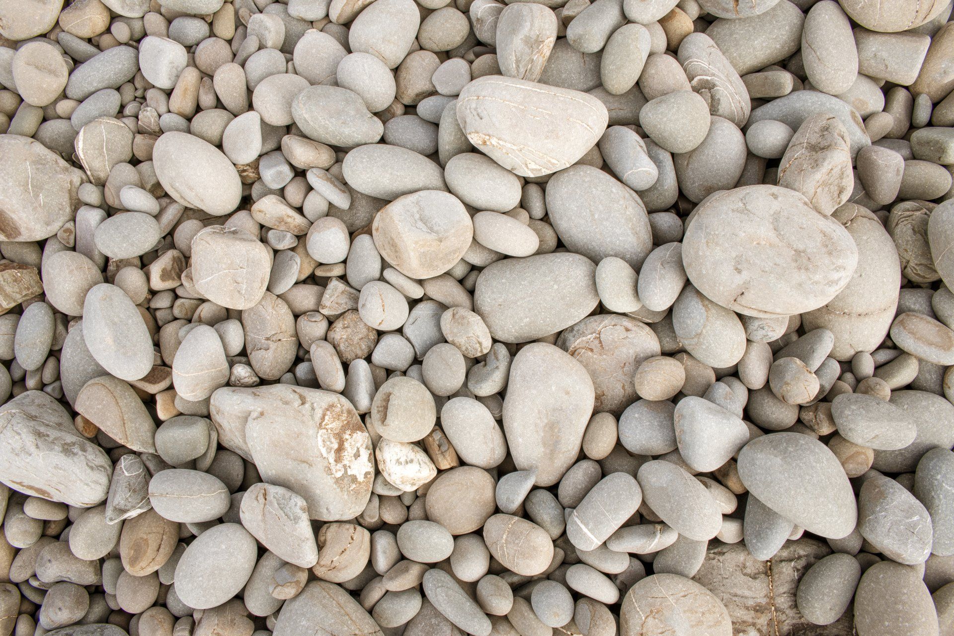 Assorted smooth beige and gray pebbles filling the frame